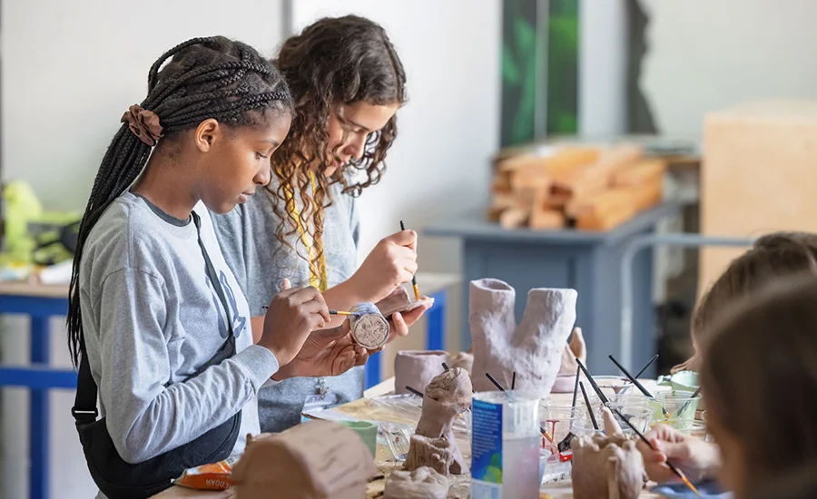 Young students painting on clay