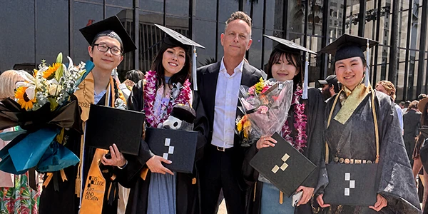 Eckardt, center, with graduating students at an Otis College commencement ceremony.