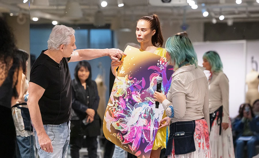 Fashion designer David Meister, left, reviews a student’s floral print during a fitting session.