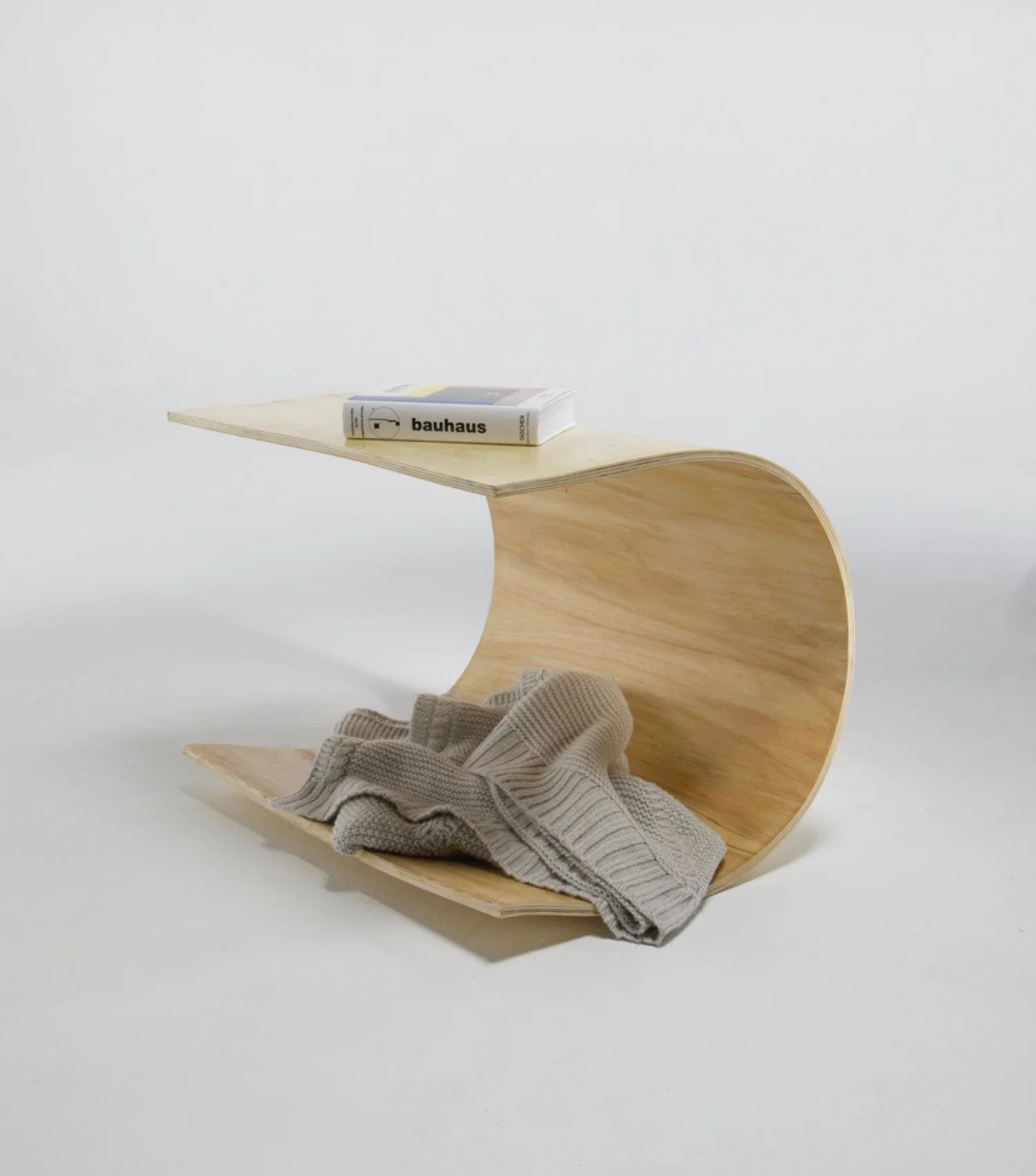 Woodwelle is a sculptural yet functional table designed for the Antigravity Project, exploring the interplay between form and balance. Crafted from bent plywood, the design embraces fluid curves to create a dynamic yet stable structure. The table’s seamless curvature serves both aesthetic and practical purposes, offering a surface for everyday use while incorporating a lower section for additional storage. Woodwelle embodies a minimalist approach, emphasizing material integrity and organic movement.