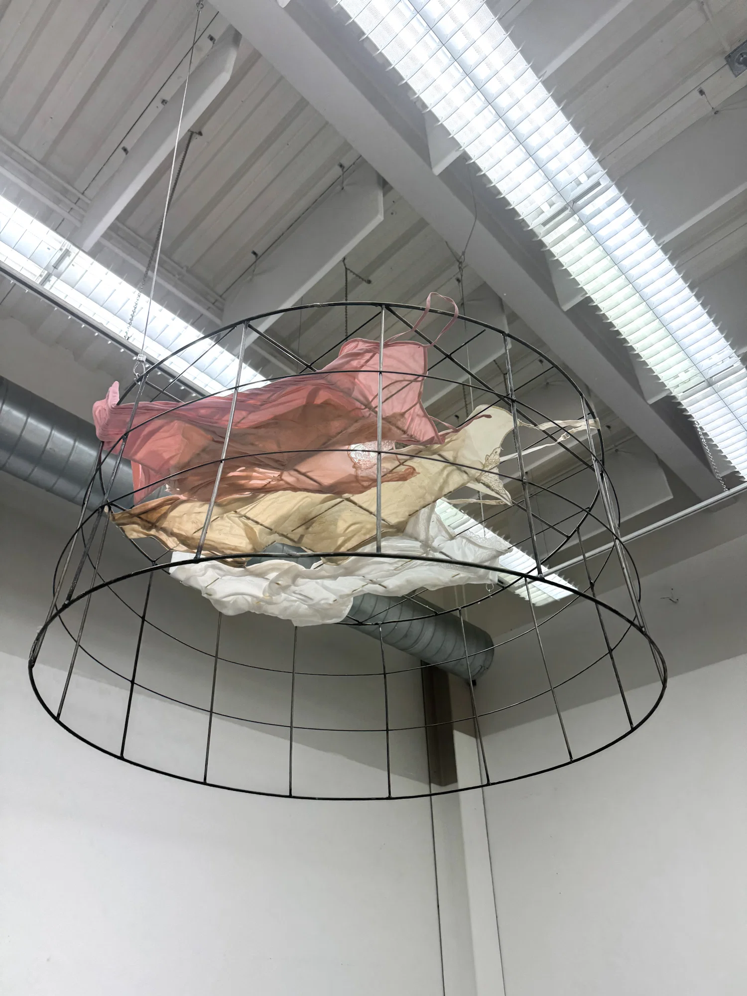 Large steel cage on ceiling with 4 dresses inside in a falling upward motion
