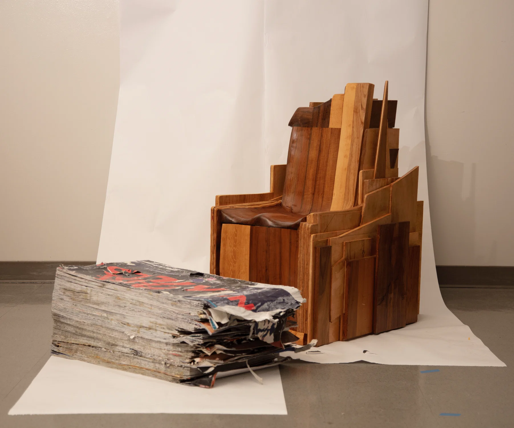 A layered scrap wood chair and layered wheat paste poster foot stool