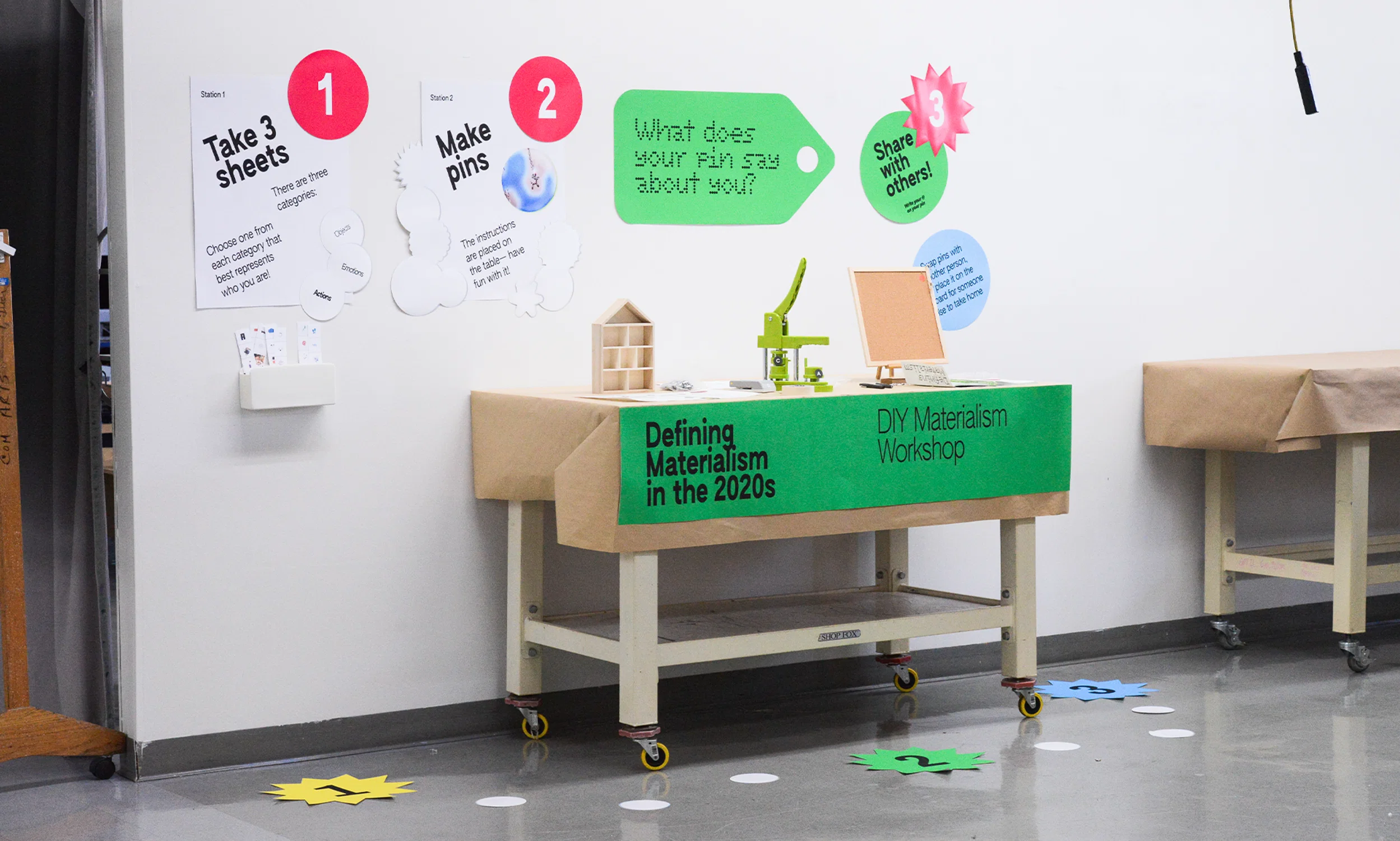 A pop-up workshop with displayed posters, a button-pin maker, and a magazine titled, "DIY Materialism in the 2020s: How do we find meaning in what we make?" Project created by Eulmin Park (2024).