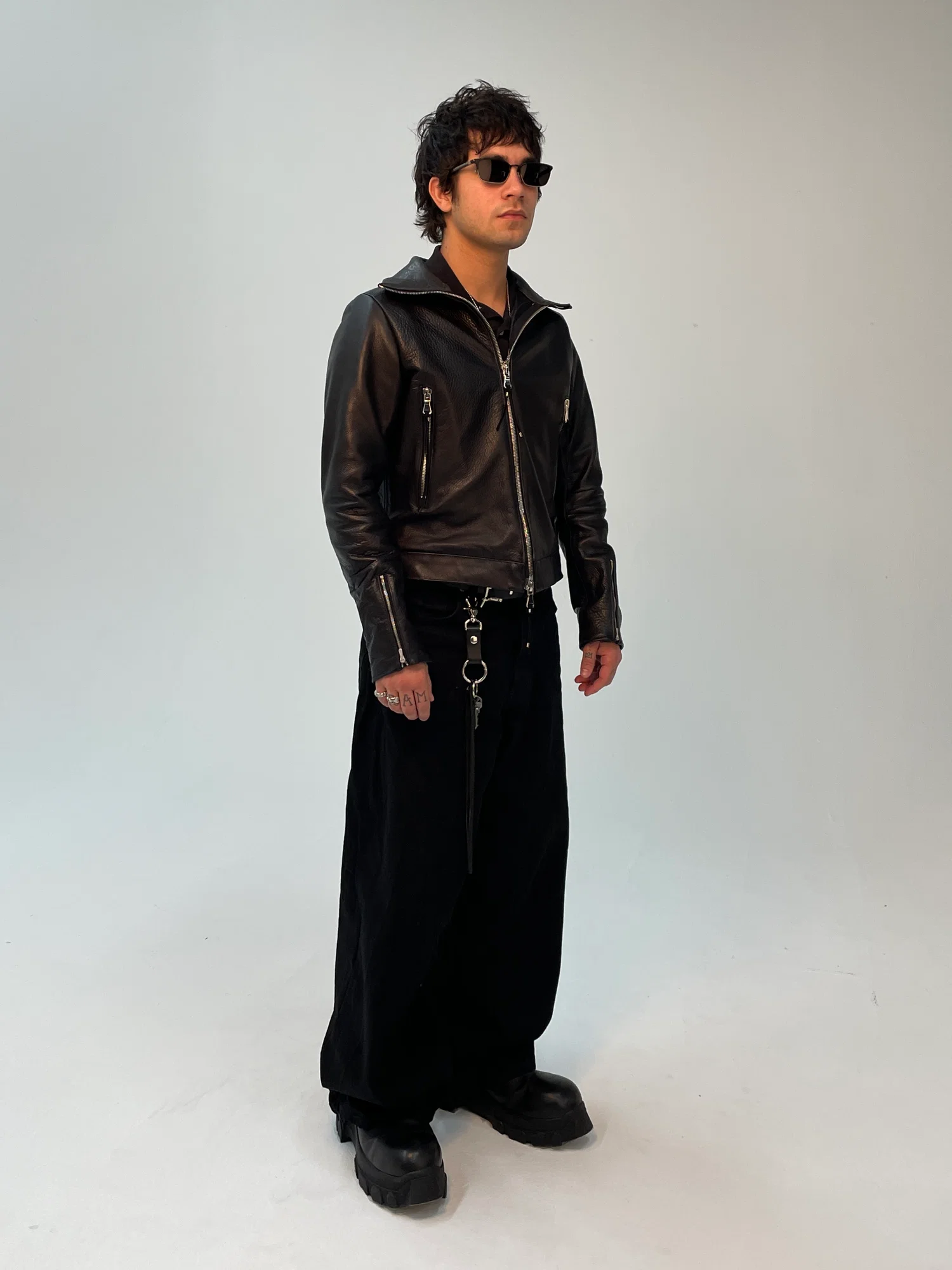 A person wearing the Rider Cut Leather Jacket. The jacket was patterned to have J-cut sleeve, cropped on body and feature high mock neck to allows for comfort and utility while riding a motorcycle