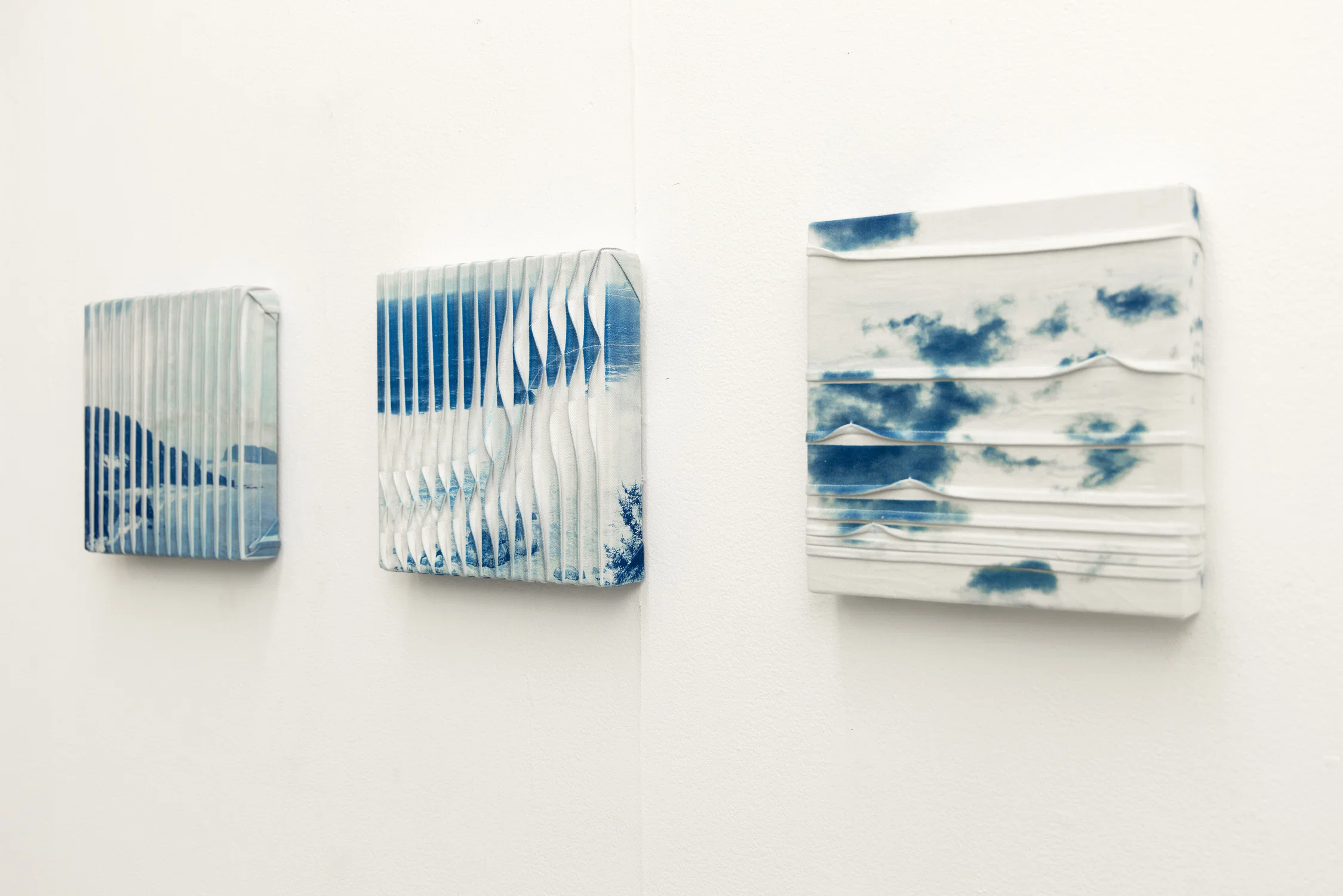 A triptych of cyanotype prints on denim stretched over panel depicting three different components of landscape photography.