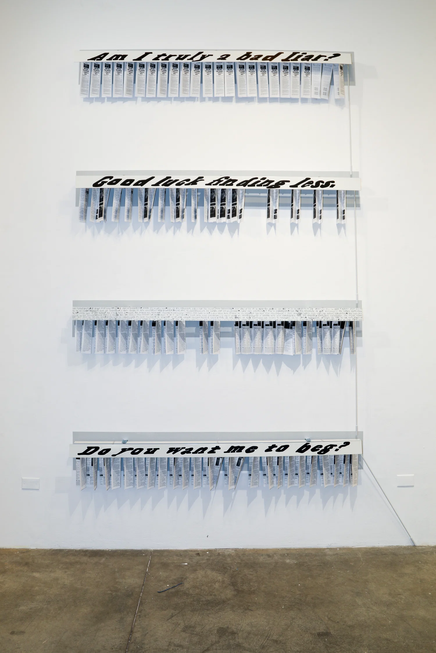 Four headrails for vertical blinds, hung from the ceiling down three feet apart. The blinds themselevs have been replaced with different editions of my pamphlet, and the headrail has been hand painted with different sentences.