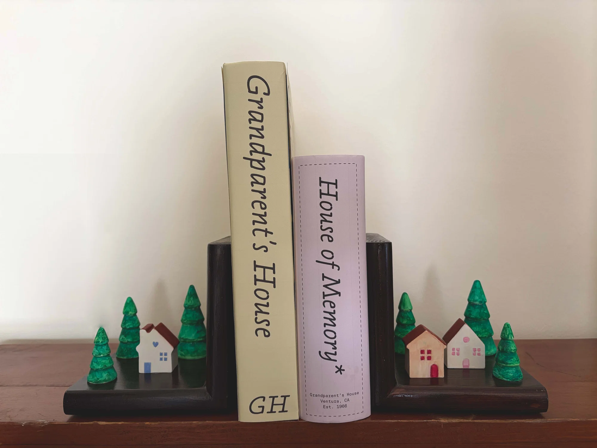 These are two books that I made one is and archive of my grandparent's house and the other has a board game that I created. They sit inbetween two bookends that I also made that have houses and trees on them.