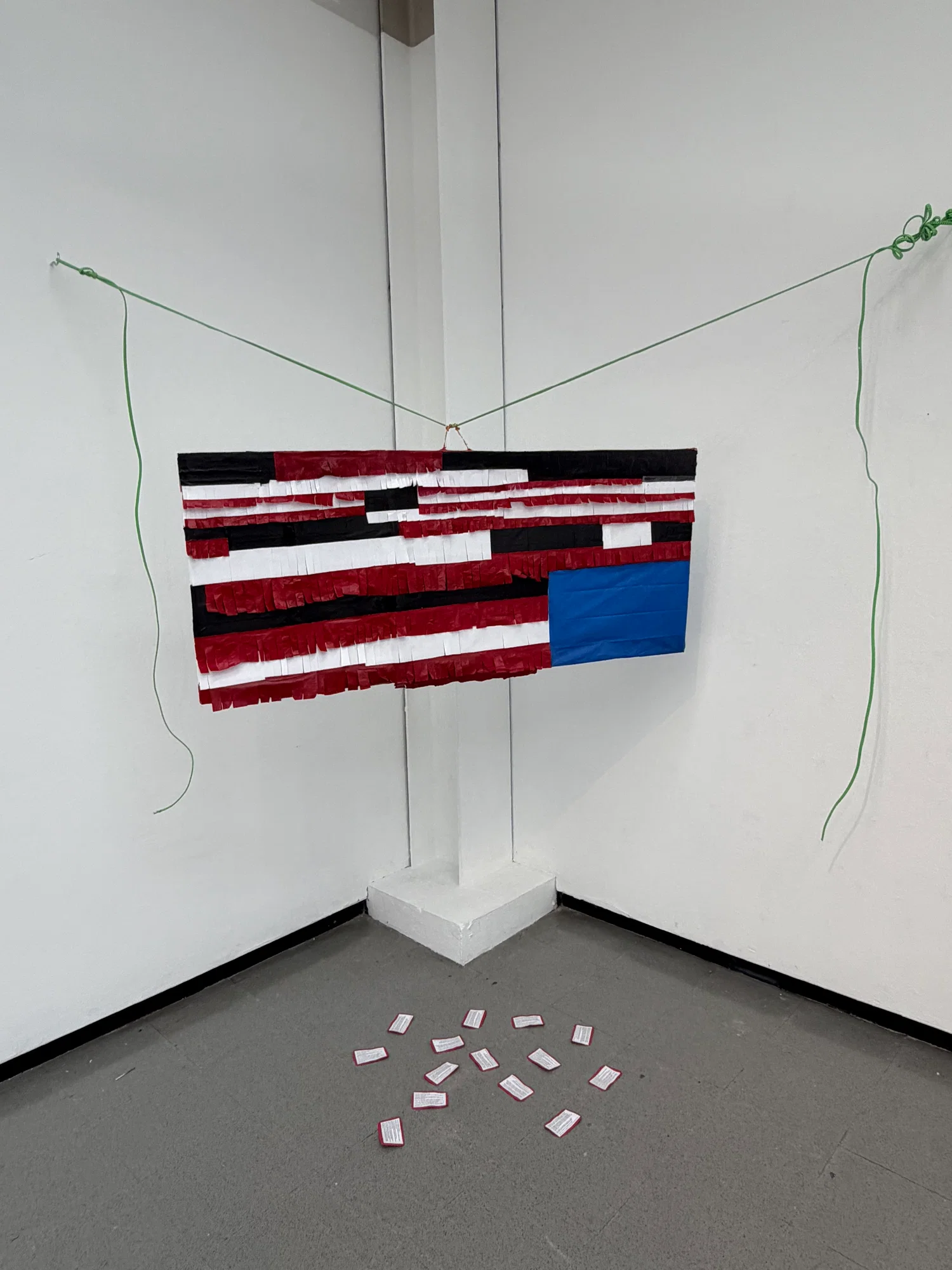 Upside down American flag piñata with redaction and red cards fallen out.