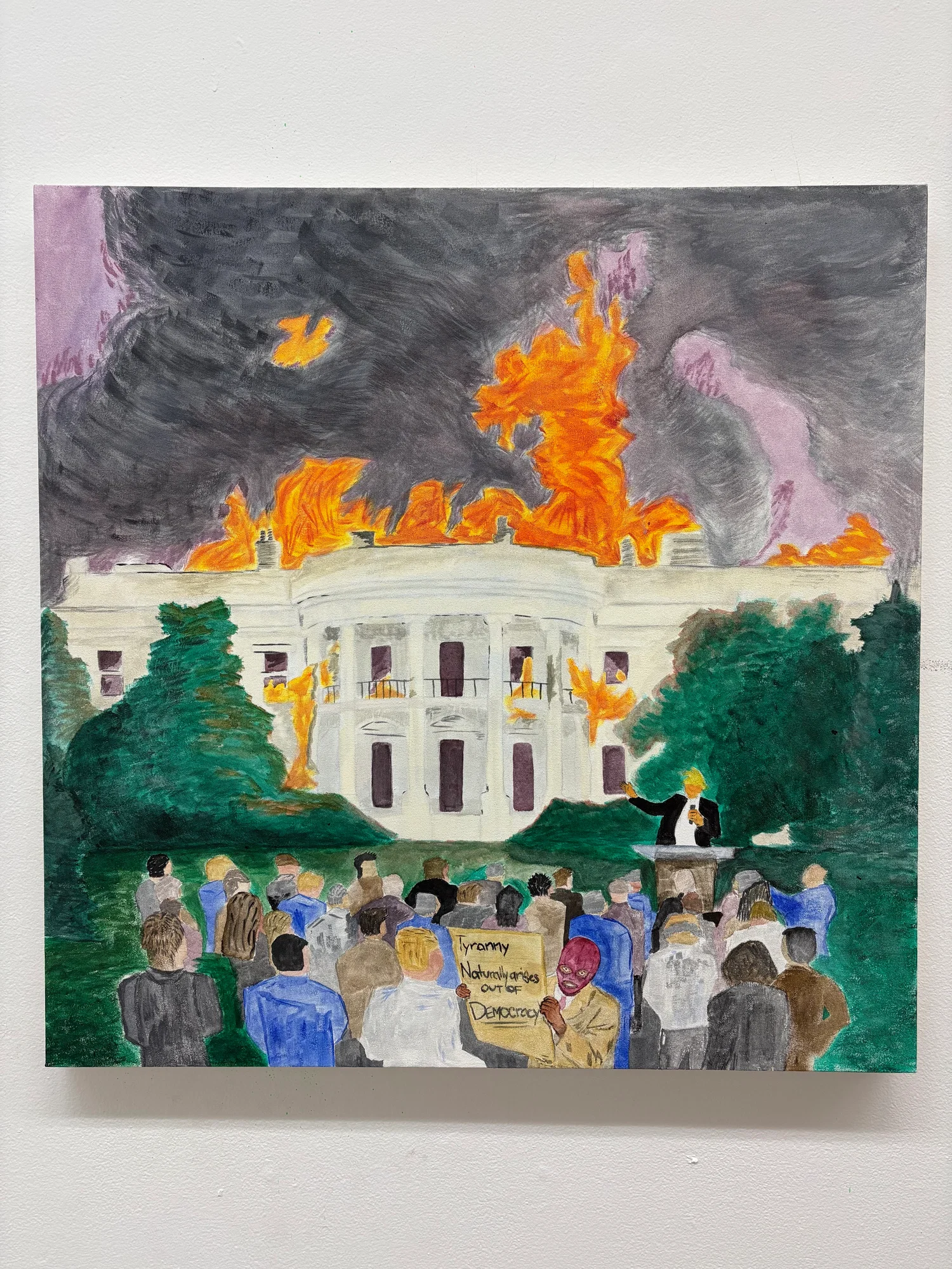 A painting shows a large white government building resembling the White House, with tall columns and a curved front. Bright orange flames are spreading across the roof and inside some of the windows, while thick, dark gray smoke fills the sky above. In the foreground, a crowd of people stands facing the building. Their backs are turned, and they are painted in muted colors, suggesting a mix of individuals. Off to the right, a man in a dark suit stands at a podium, raising one hand as if giving a speech. Near the center of the crowd, one person wearing a pink face covering holds a sign that reads, “Tyranny naturally arises out of democracy.” The overall scene feels chaotic and tense, with the burning building contrasting against the calm but watchful crowd.