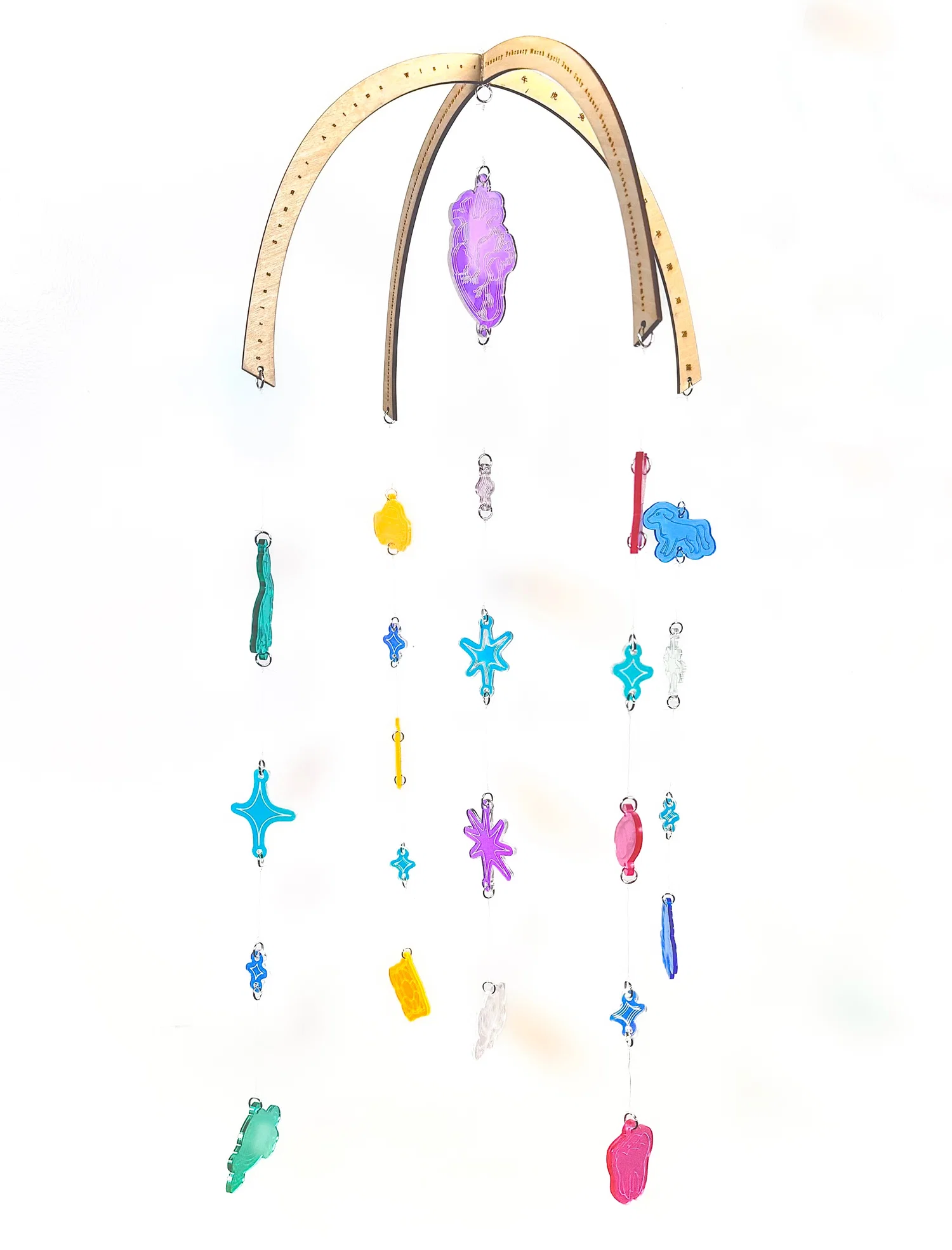 Photograph of a hanging mobile in front of plain white background. The frame is made of wood with wood-burned designs along its rim of various modes of calendar/time. The various colorful acrylic pieces, engraved with numerous images, are hung with clear fishing reel.