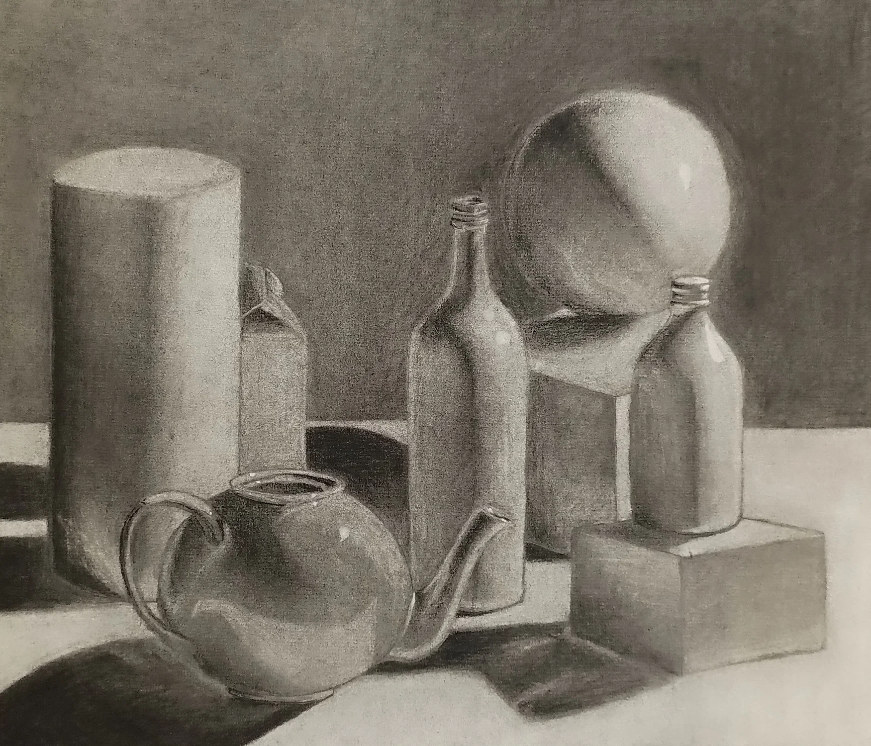 A charcoal grayscale still life drawing of everyday objects arranged on a table. From left to right: a tall cylinder, a small carton, a rounded teapot with a curved spout and handle, two glass bottles, and a sphere resting on a stand atop a cube. Light falls from the upper left, creating strong highlights and deep shadows that emphasize the shapes and surfaces of each object.