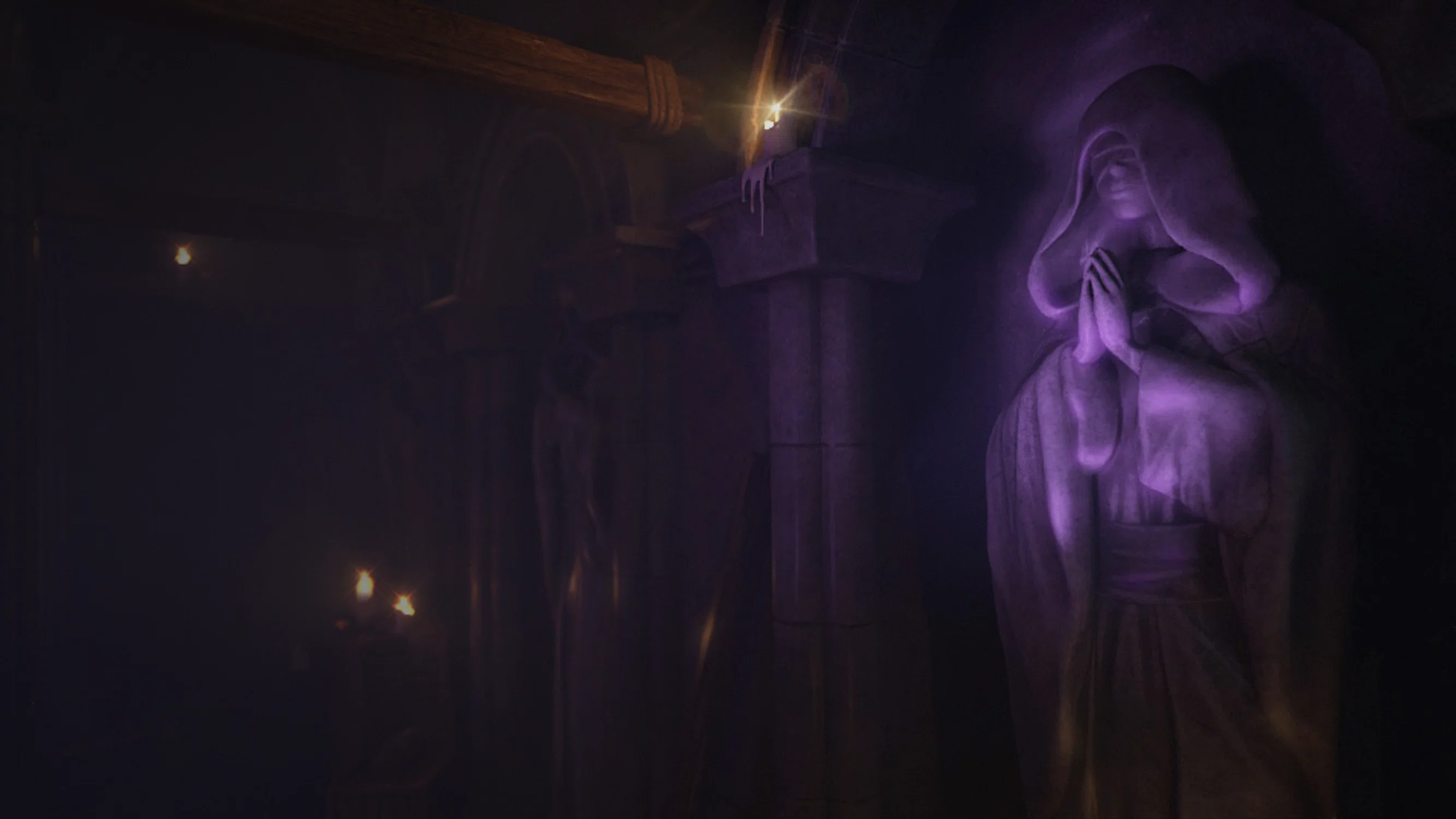 A hooded stone statue in a prayer position is carved into the wall of a dark, subterranean chamber. The figure is bathed in a mysterious purple glow, while flickering candles on stone pillars cast long shadows and a warm, dim light throughout the cavernous hall.