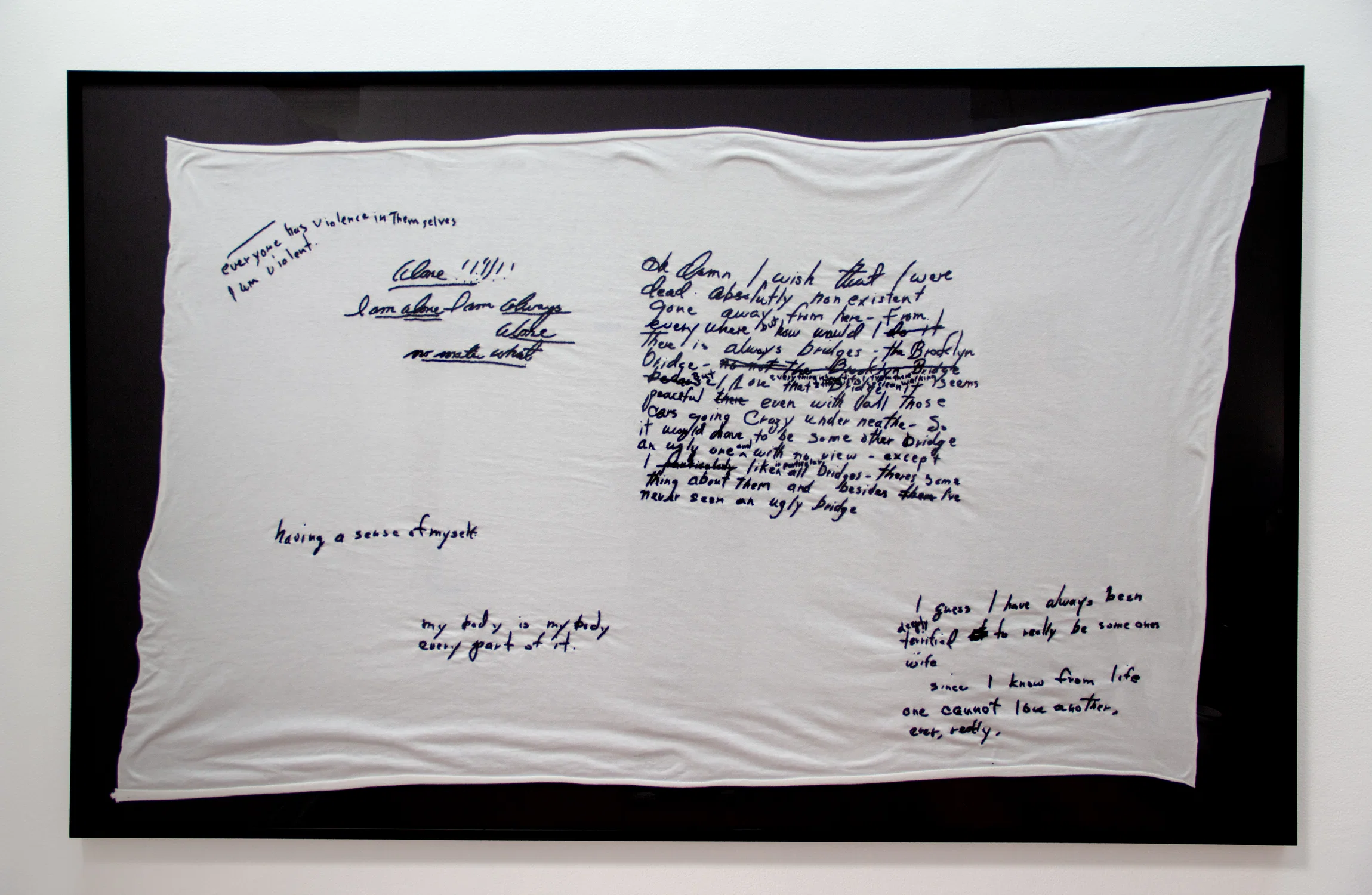 White blanket framed, floating on a black background with black frame. Hand stitched embroidery of Marilyn Monroe's personal writing.