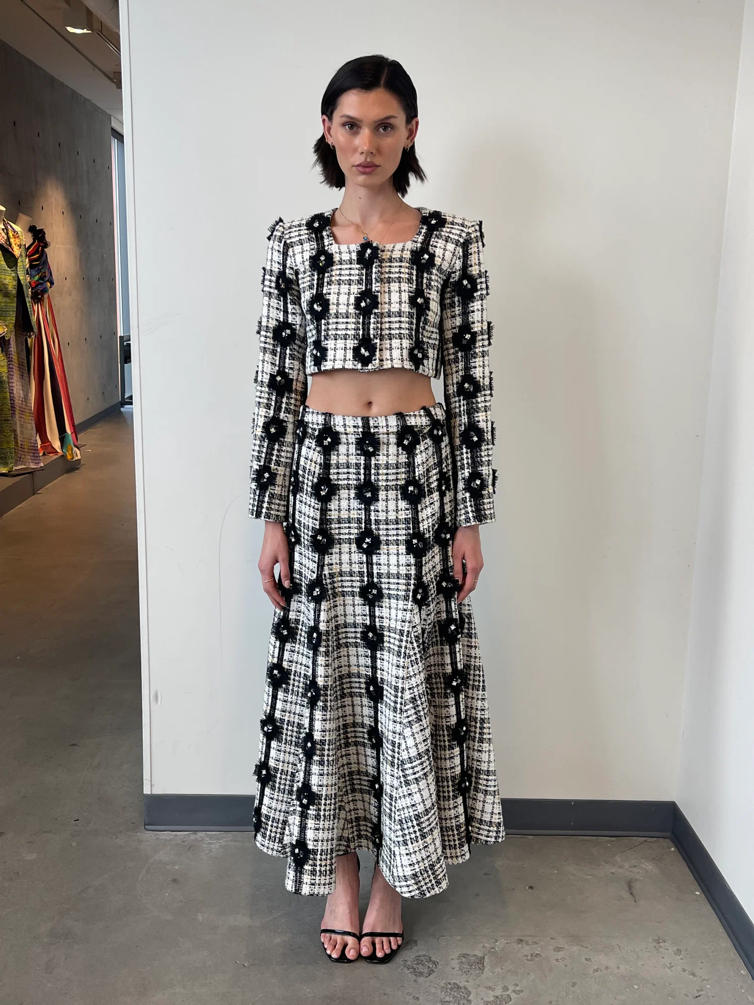 Full view of model wearing an embellished plaid cropped jacket and matching flared maxi skirt.