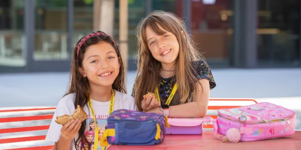 Two female Summer Youth Camp students eating lunch in the Otis Commons