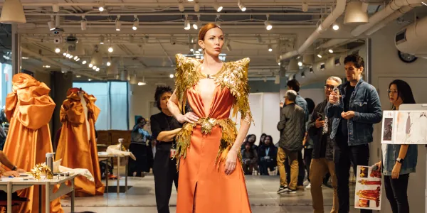 Model wearing a bronze colored fancy dress at a fitting