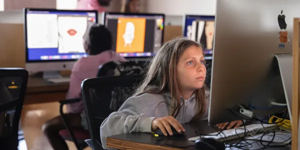 Female Summer Youth Camp student working at a computer in a computer lab
