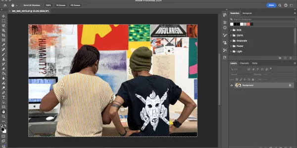 An Adobe Photoshop screen window editing an image of two Graphic Design students browsing a table full of Graphic Design work