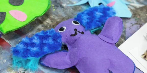 Purple humanoid toy with blue and teal hair growing out of the sides of its head