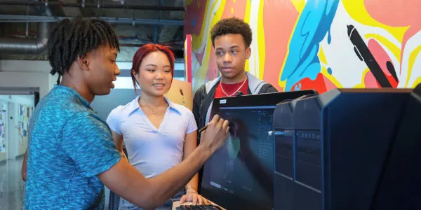 Game design student wrking at a computer with two other students looking on