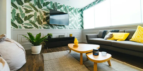 Living room with sofa, 2-piece coffee table, flat screen TV on wall, credenza, and potted plant