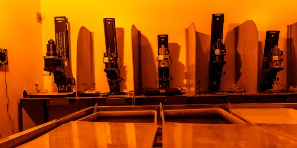 A photographic dark room with developing trays in front and enlargers behiind