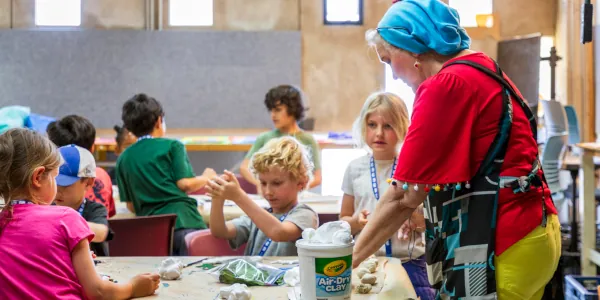 Female instructor with a half dozen Summer Youth Camp students working on their clay projects
