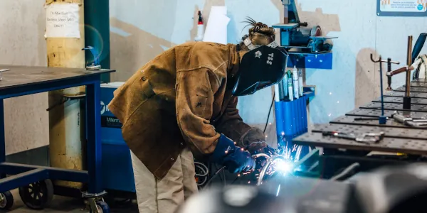 Student welding in the Otis wood/metal shop