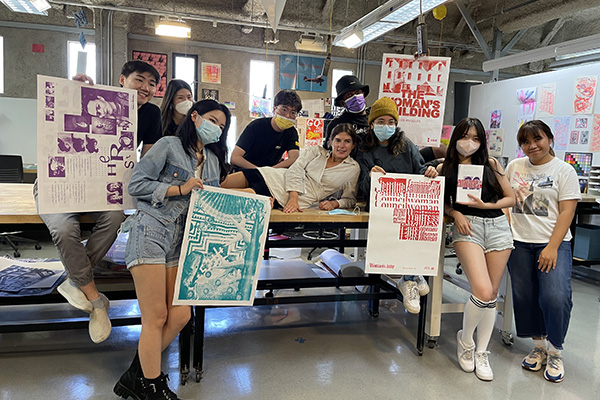 Students holding up various works