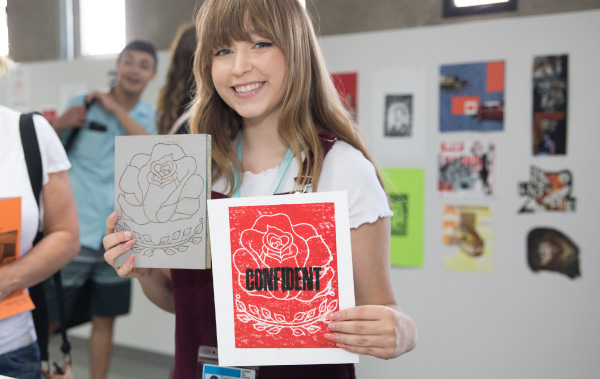 Student holding up their artwork to camera