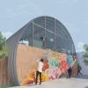 This image depicts the exterior of the homeless youth shelter where people are hanging out outside as a man paints a mural on the end wall of the quonset hut. 