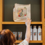 Woman reaching for a Huntington Library tote bag