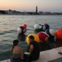 3 travel study students sit on a quay with large billiard ball shaped floats in the water