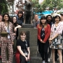11 travel study students and their instructor gathered aroud the statue of a dog