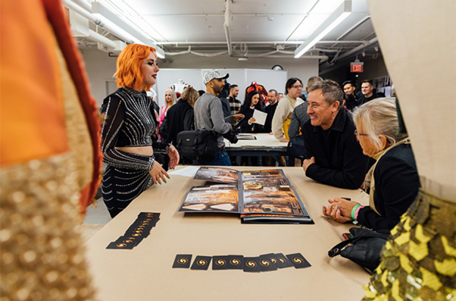 A Fashion Design student shows their portfolio to guests during O-Launch.